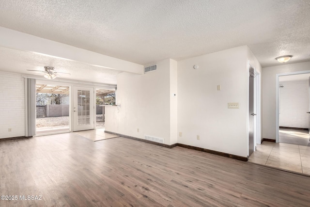 empty room featuring wood finished floors, a textured ceiling, and visible vents
