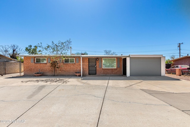 ranch-style house featuring a garage, driveway, brick siding, and fence