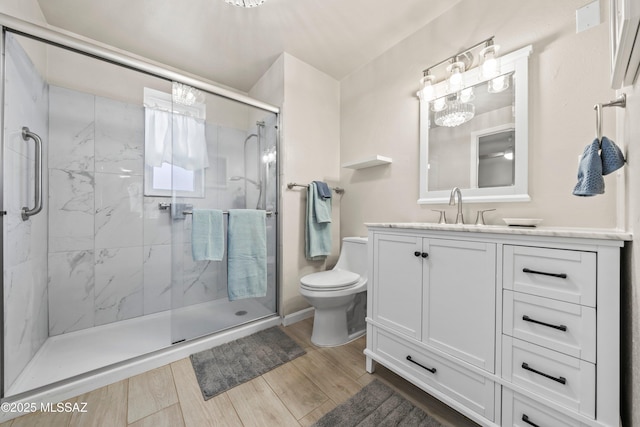 bathroom featuring a marble finish shower, vanity, toilet, and wood finished floors