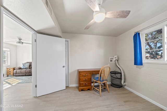 home office with a ceiling fan, visible vents, light wood finished floors, and baseboards