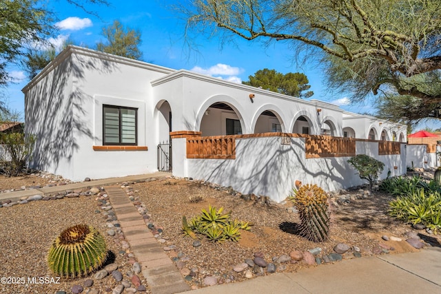 mediterranean / spanish-style house featuring a fenced front yard and stucco siding