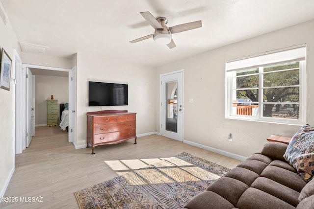 living area with ceiling fan, light wood-type flooring, and baseboards