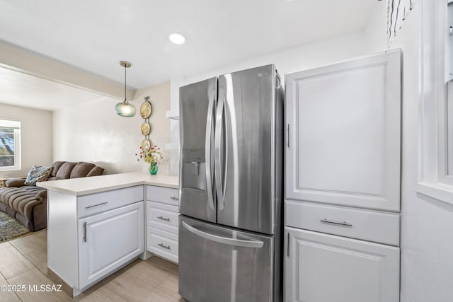 kitchen with a peninsula, white cabinetry, open floor plan, light countertops, and stainless steel refrigerator with ice dispenser