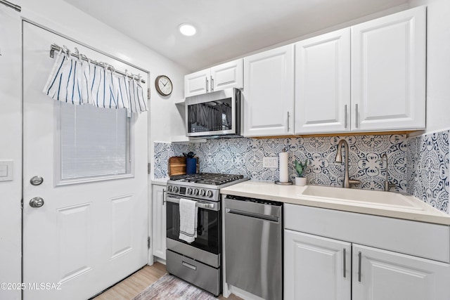 kitchen featuring stainless steel appliances, white cabinetry, a sink, and tasteful backsplash