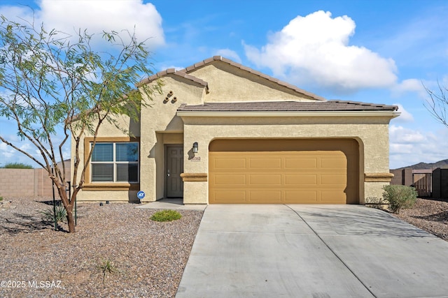 view of front of property featuring a garage, fence, a tile roof, concrete driveway, and stucco siding