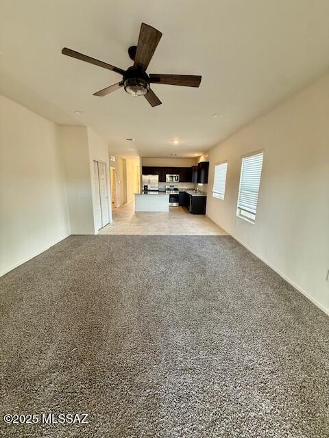 unfurnished living room with ceiling fan and light colored carpet