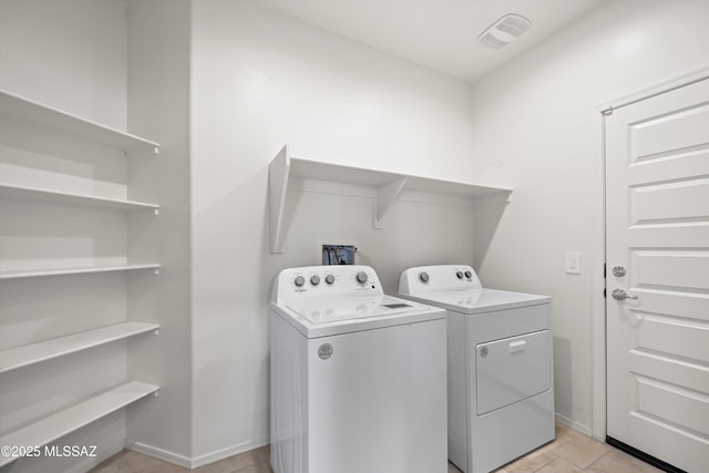 washroom featuring light tile patterned floors, visible vents, separate washer and dryer, laundry area, and baseboards