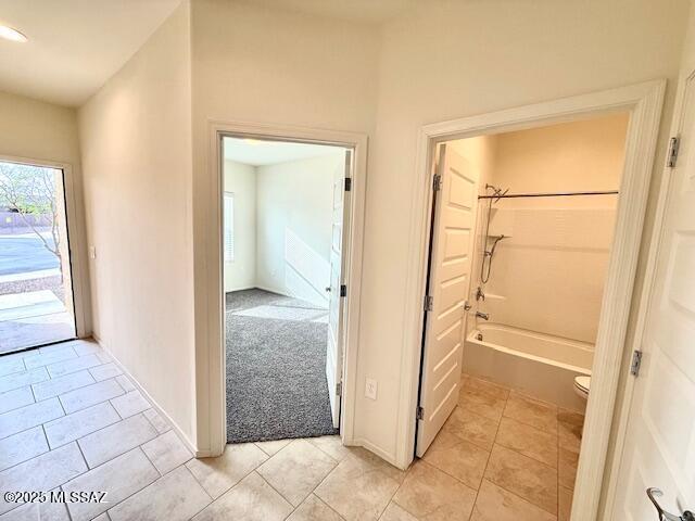 full bathroom featuring toilet, tile patterned flooring, and  shower combination