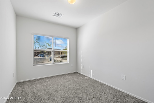 empty room featuring carpet floors, visible vents, and baseboards