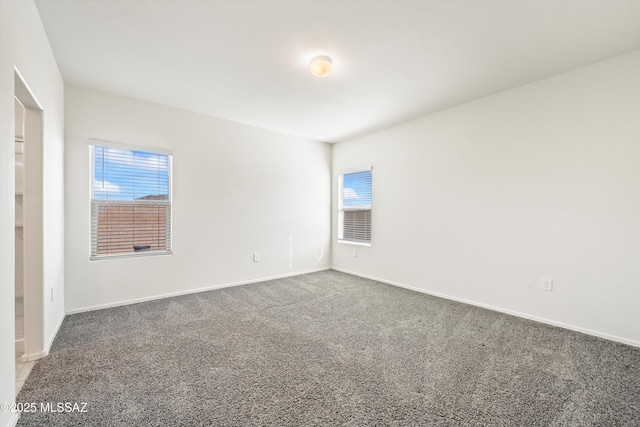 carpeted spare room featuring plenty of natural light and baseboards