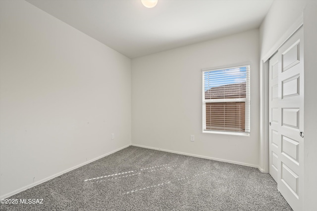 carpeted spare room featuring baseboards