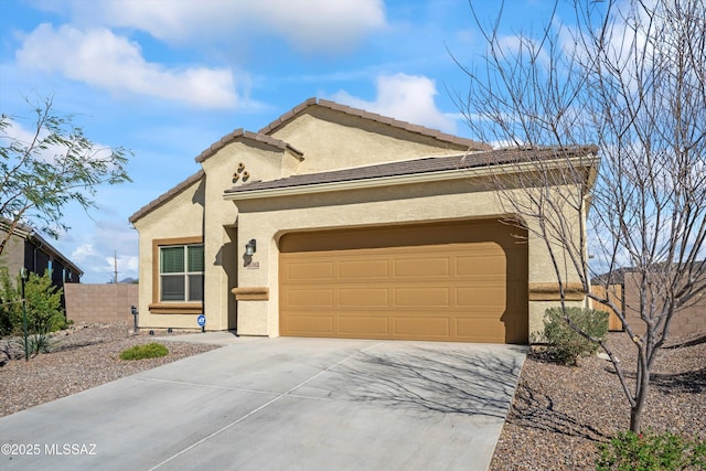 view of front of property with an attached garage, fence, driveway, a tiled roof, and stucco siding