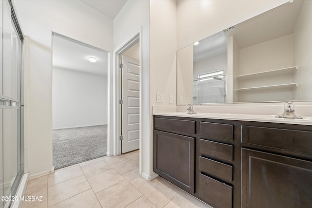 full bathroom featuring a shower with door, double vanity, visible vents, a sink, and tile patterned floors