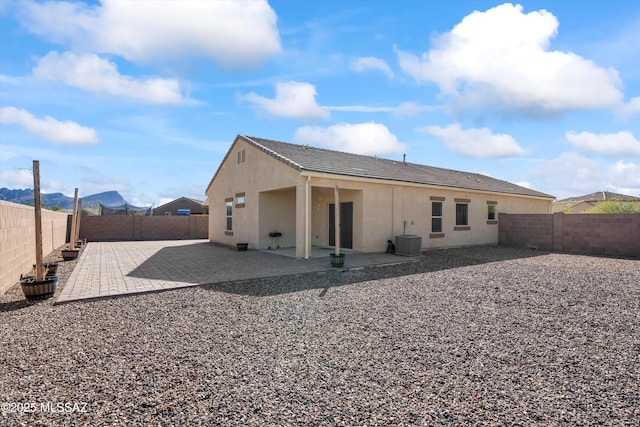 rear view of house with cooling unit, a patio area, a fenced backyard, and stucco siding