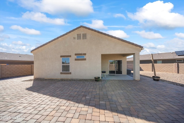 back of property with a fenced backyard, a patio, and stucco siding