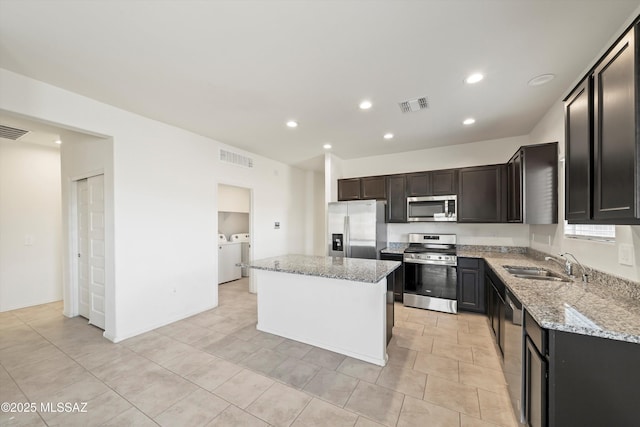 kitchen with visible vents, a center island, stainless steel appliances, separate washer and dryer, and a sink