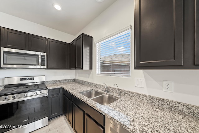 kitchen featuring light tile patterned floors, recessed lighting, a sink, appliances with stainless steel finishes, and light stone countertops