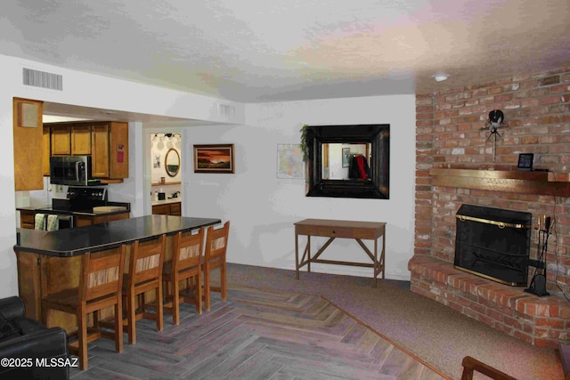 dining room with a textured ceiling, a brick fireplace, and visible vents