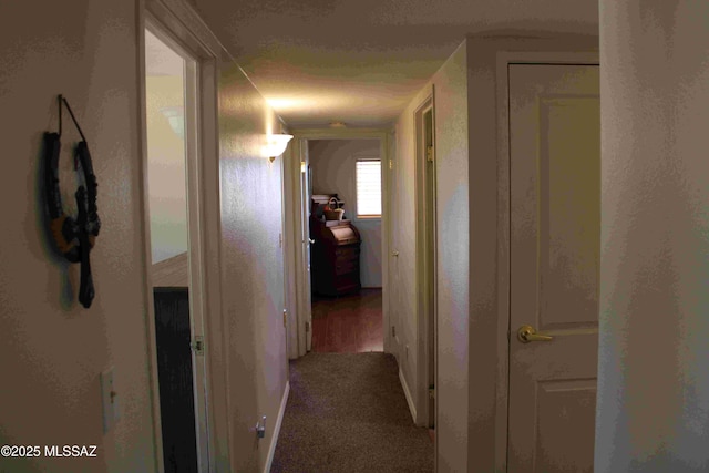 corridor with a textured ceiling and carpet flooring