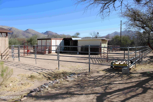 view of horse barn with a rural view and a mountain view