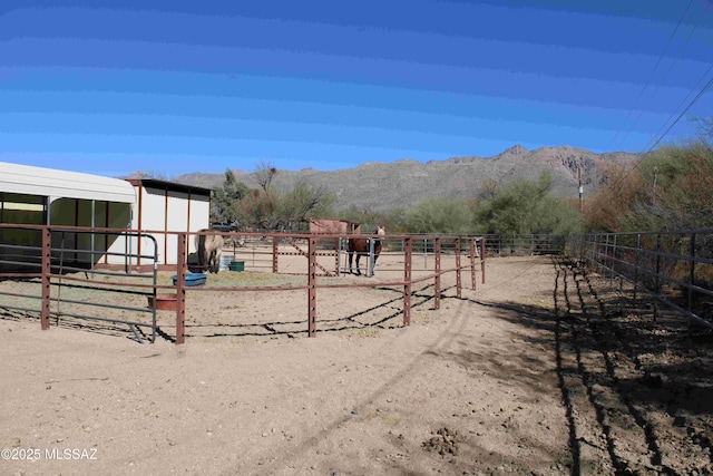 view of yard featuring an exterior structure, a mountain view, an outdoor structure, and a rural view