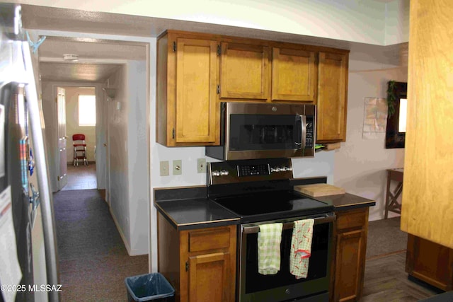 kitchen featuring appliances with stainless steel finishes, brown cabinetry, and dark countertops