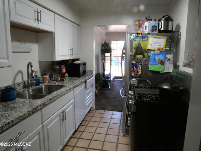 kitchen featuring light tile patterned floors, white cabinets, appliances with stainless steel finishes, light stone countertops, and a sink