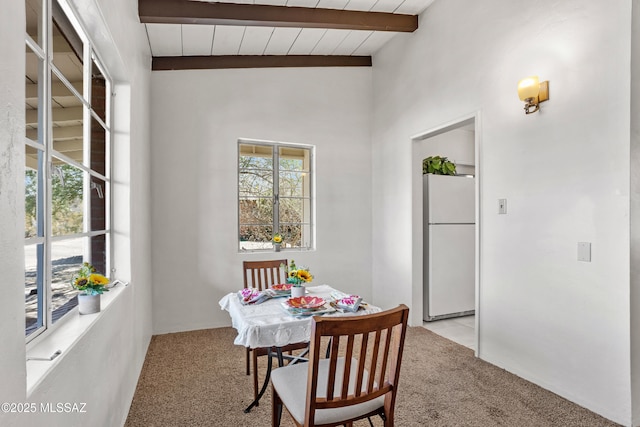 dining space with plenty of natural light, light colored carpet, and beamed ceiling