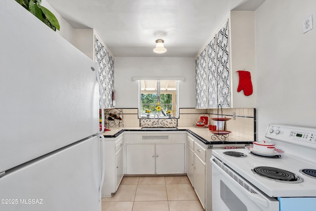 kitchen featuring light tile patterned floors, tasteful backsplash, white cabinets, a sink, and white appliances