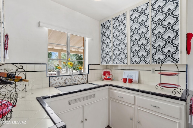 kitchen with tasteful backsplash, white cabinets, and a sink