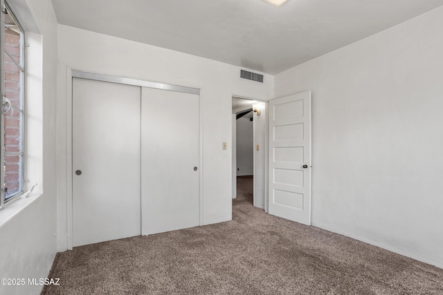 unfurnished bedroom featuring a closet, carpet, and visible vents