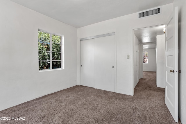 unfurnished bedroom with a closet, carpet flooring, and visible vents