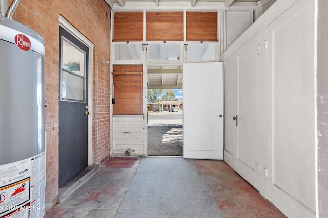 entryway with water heater, brick wall, and concrete flooring