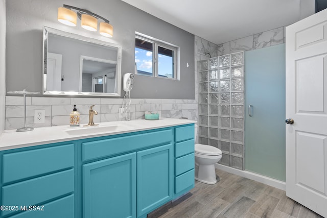 full bath featuring a stall shower, wood finished floors, vanity, and tile walls