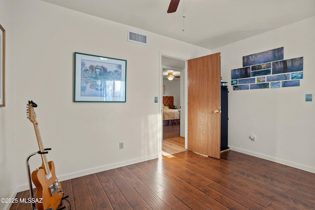 spare room with a ceiling fan, visible vents, baseboards, and hardwood / wood-style flooring