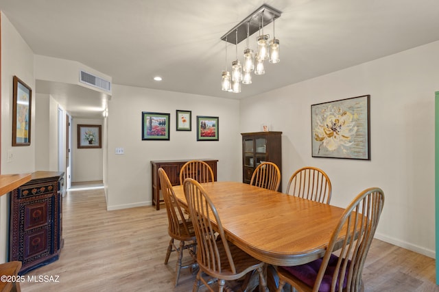 dining room with baseboards, visible vents, and light wood finished floors