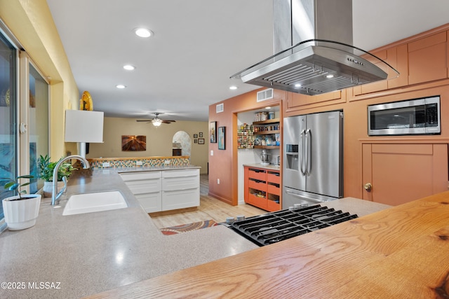 kitchen with stainless steel appliances, light countertops, island exhaust hood, and a sink