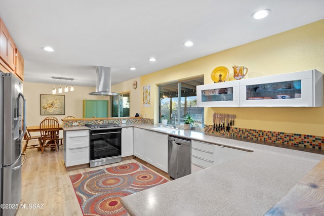 kitchen with a peninsula, a sink, appliances with stainless steel finishes, light wood-type flooring, and island exhaust hood