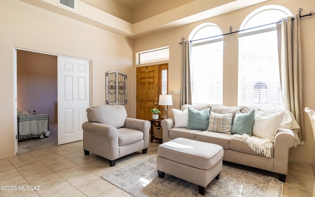 living area featuring light tile patterned floors, a high ceiling, and visible vents