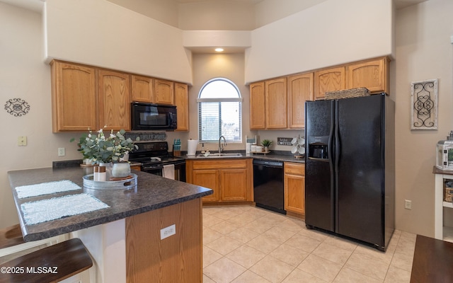 kitchen with dark countertops, a high ceiling, a sink, a peninsula, and black appliances