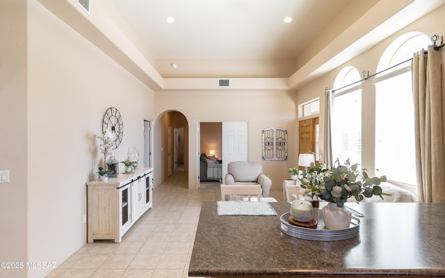 living area featuring arched walkways, light tile patterned floors, visible vents, and recessed lighting