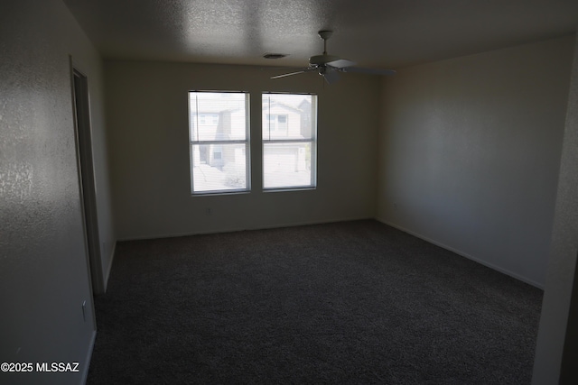 spare room featuring baseboards, visible vents, a ceiling fan, dark colored carpet, and a textured ceiling