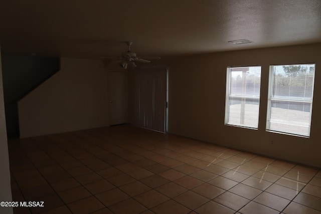 tiled empty room featuring visible vents, ceiling fan, and a textured ceiling