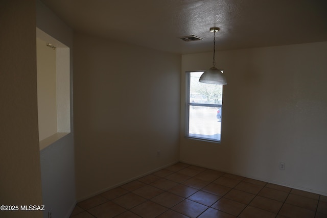 empty room featuring a textured ceiling, tile patterned flooring, and visible vents