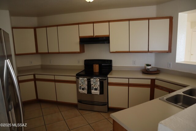 kitchen with light tile patterned floors, under cabinet range hood, a sink, light countertops, and appliances with stainless steel finishes