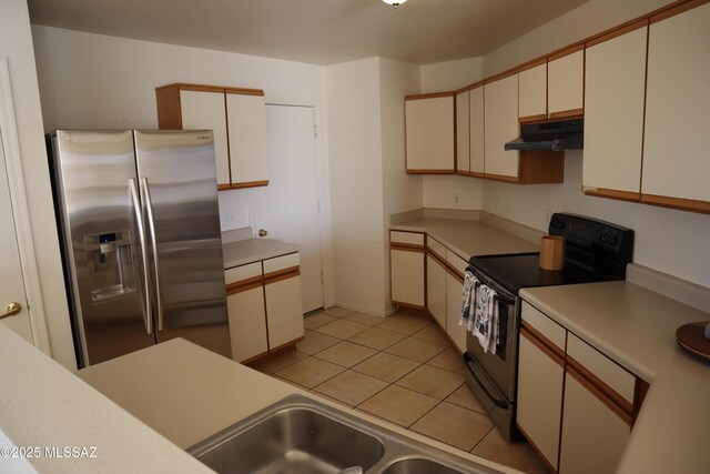 kitchen featuring light tile patterned floors, stainless steel fridge, light countertops, under cabinet range hood, and black range with electric cooktop