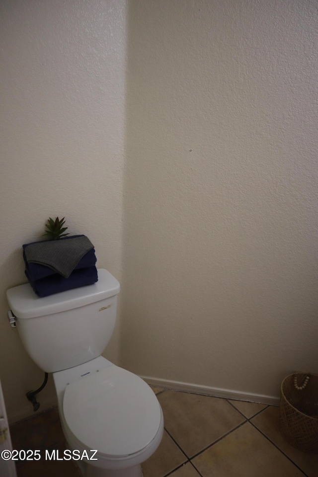 bathroom featuring tile patterned flooring, baseboards, and toilet