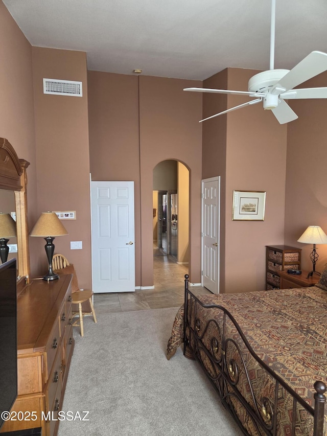 carpeted bedroom with arched walkways, visible vents, and a high ceiling