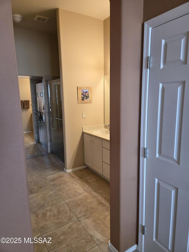 bathroom with a stall shower, baseboards, visible vents, tile patterned floors, and vanity