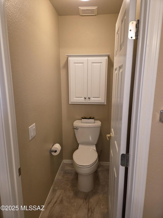 bathroom with baseboards, visible vents, and toilet